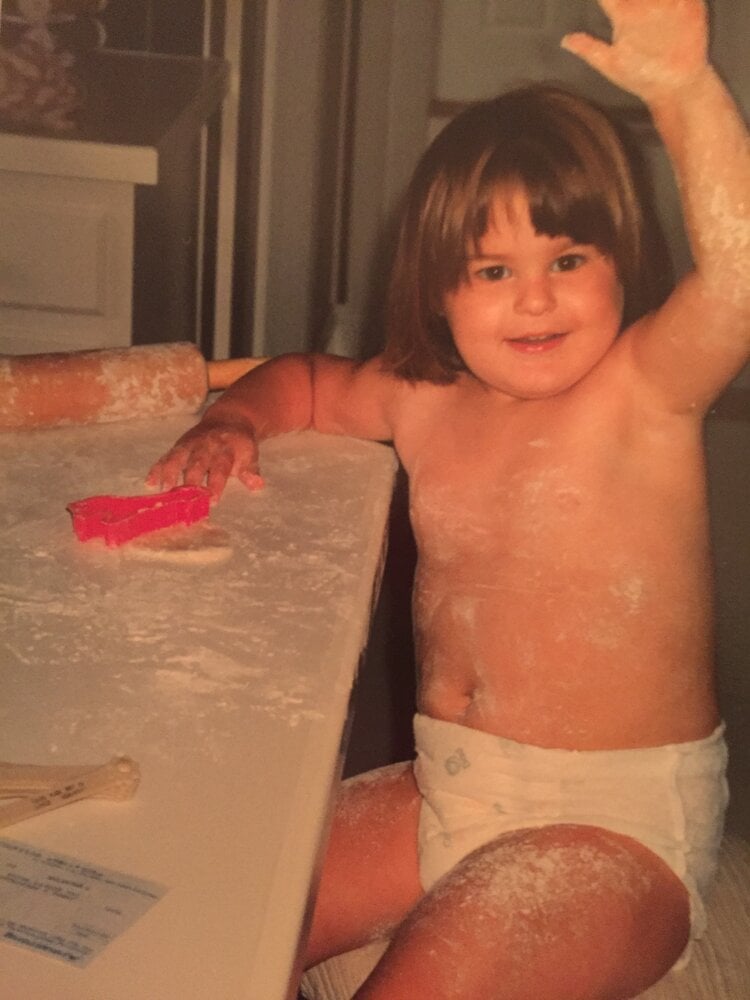 jocelyn as a toddler covered in flour cutting our giraffe cookies