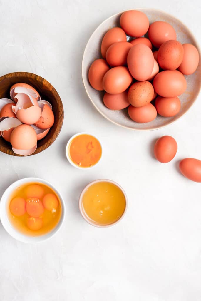 fresh eggs, whole eggs, egg whites, egg shells, and egg yolks in bowls
