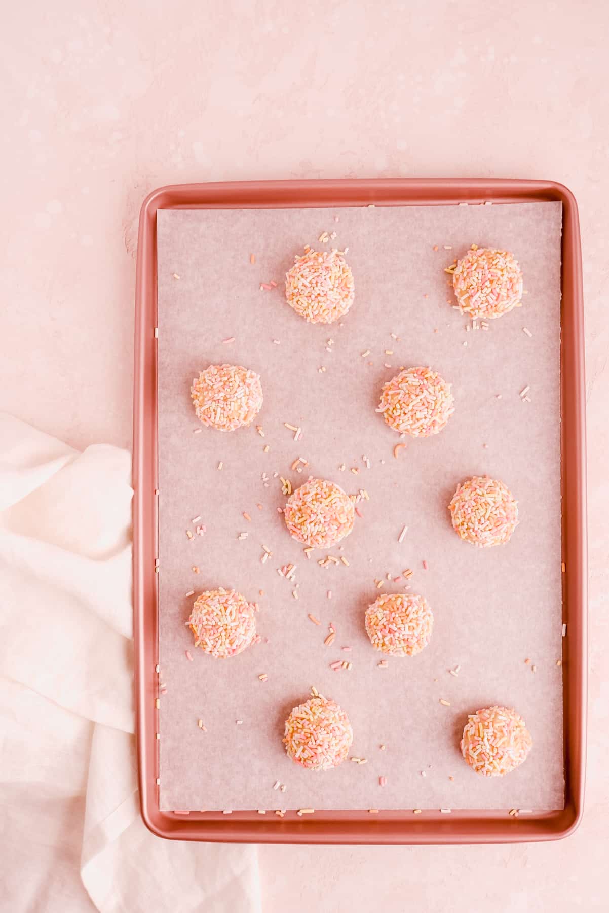 a sheet pan of birthday cake cookie dough balls covered in rainbow sprinkles