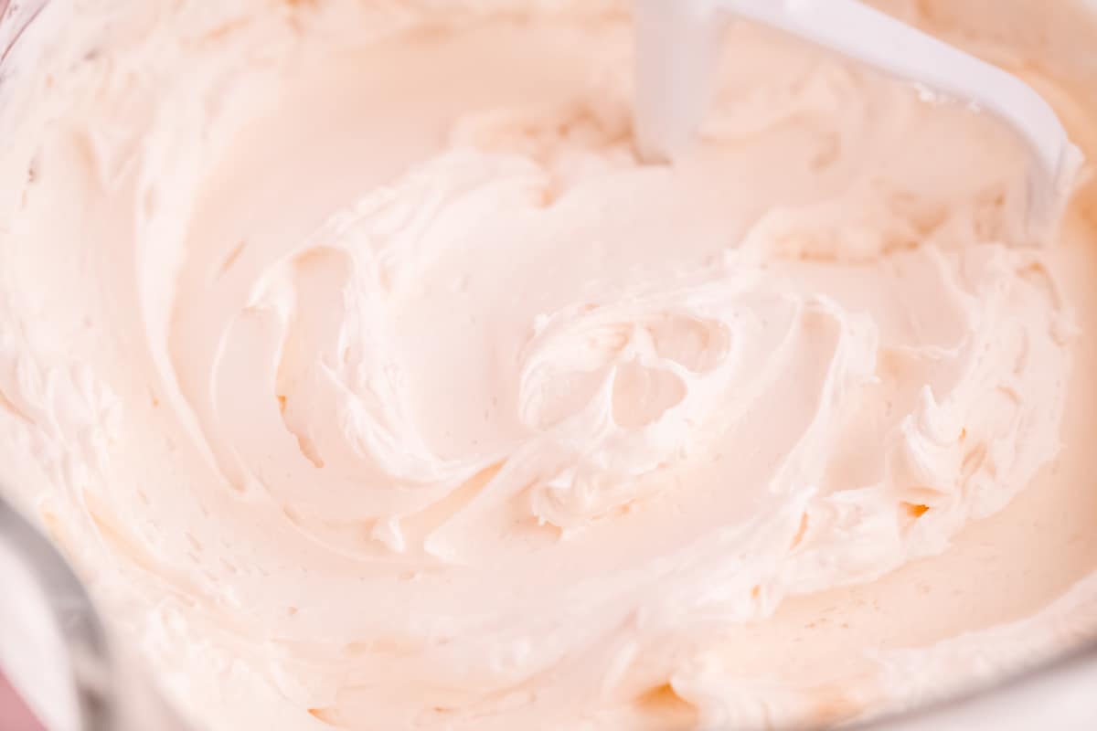 a kitchenaid mixer glass bowl and beater filled with easy vanilla buttercream frosting