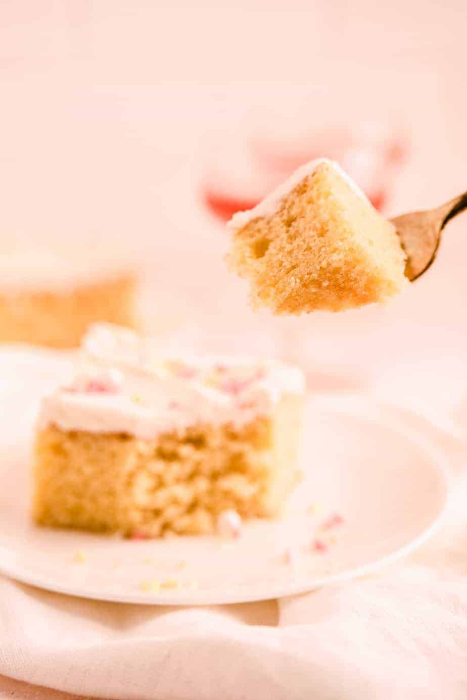 a cut slice of sheet cake with buttercream and sprinkles on top with a bite taken out on a fork