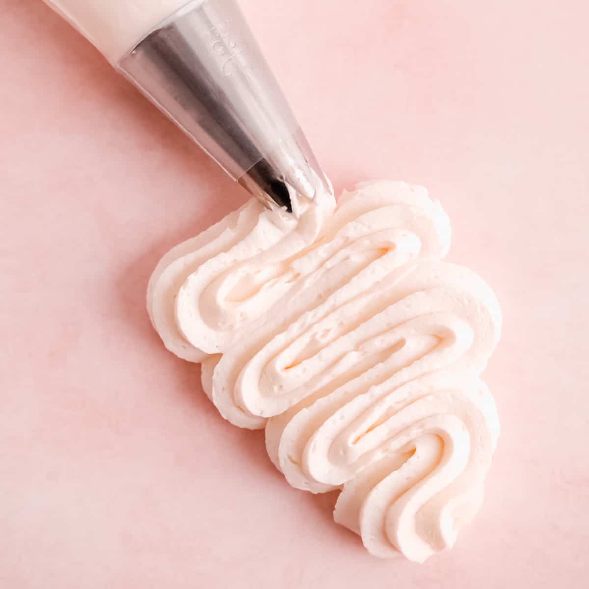 easy vanilla buttercream frosting being squiggled on a surface from a pastry bag fitted with a star piping tip