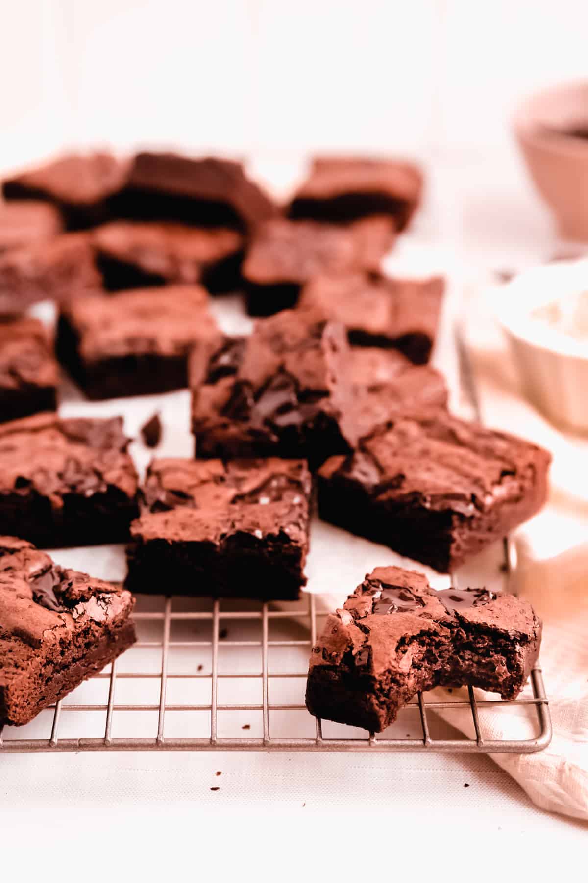 cut squares of fudgy gluten free brownies scattered on a wire cooling rack