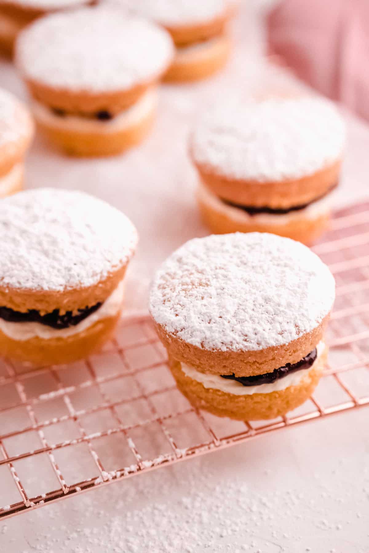 mini victoria sponge cakes filled with jam on a wire cooling rack