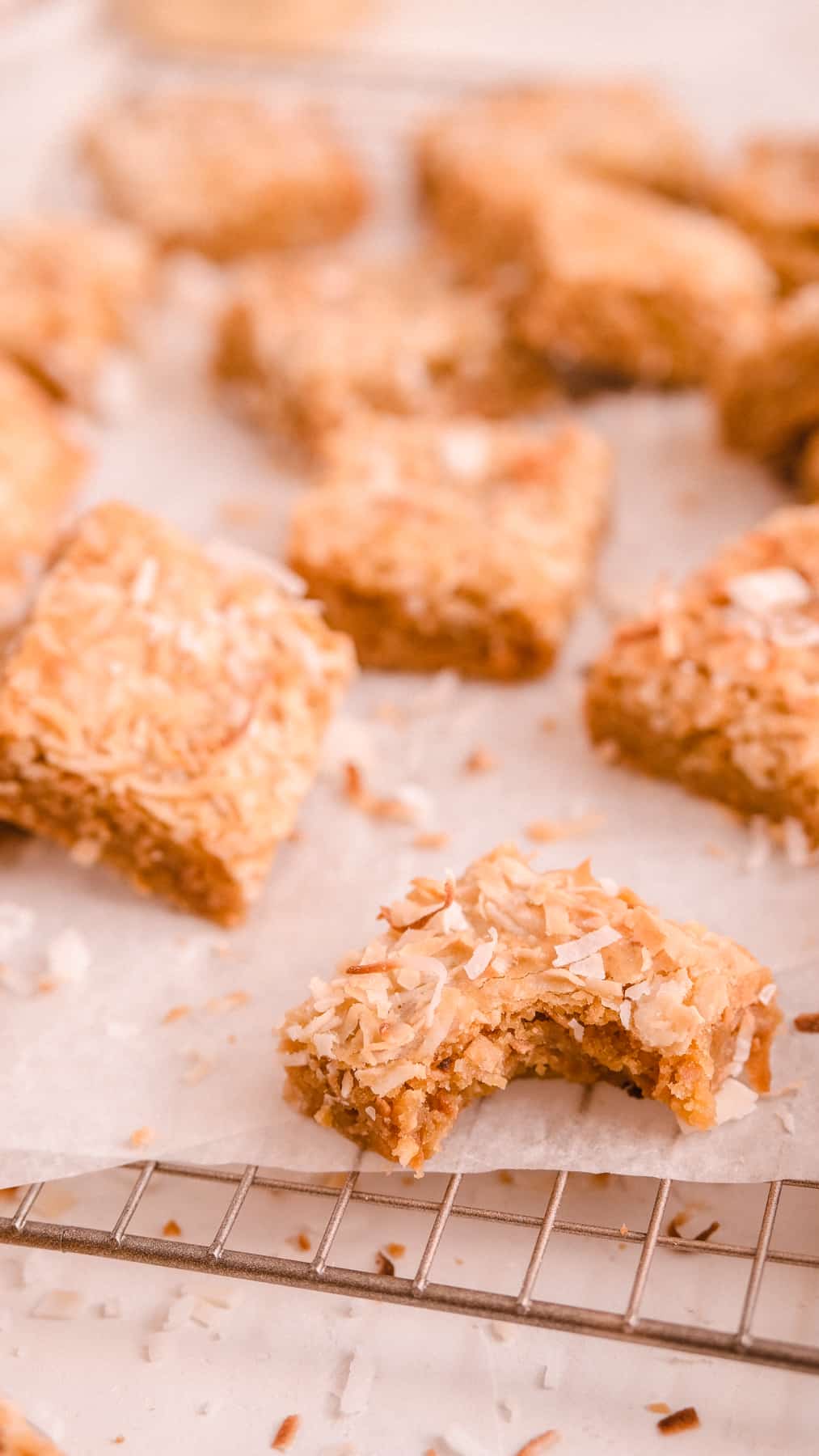 coconut butterscotch cookie bars on a wire rack with a bite out of one