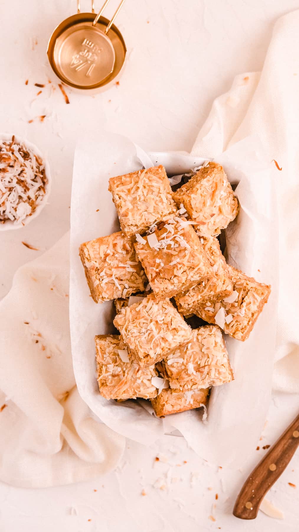 a rectangular ceramic dish filled with squares of coconut butterscotch cookie bars