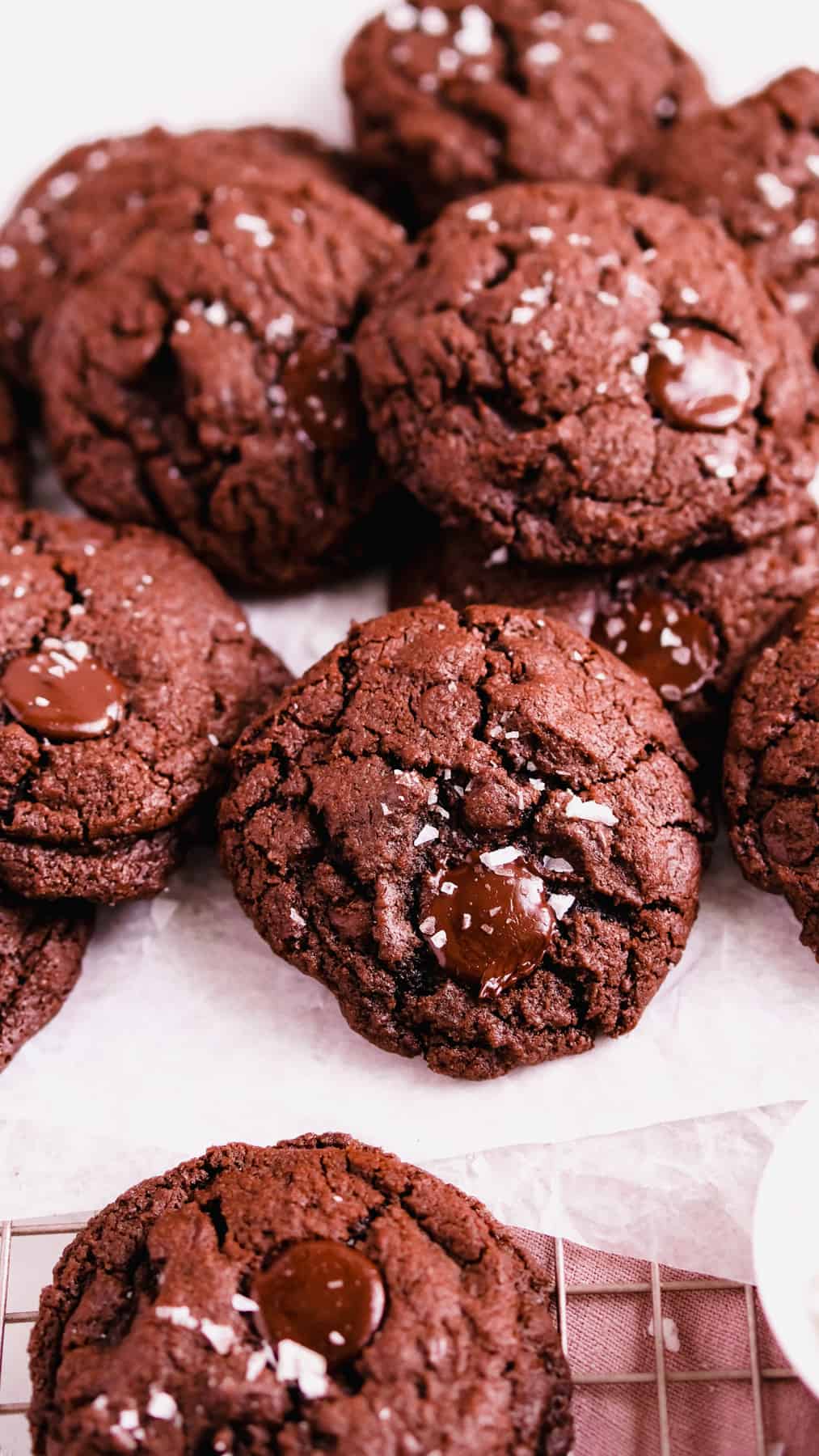 double chocolate chip cookies on a wire rack covered in parchment.