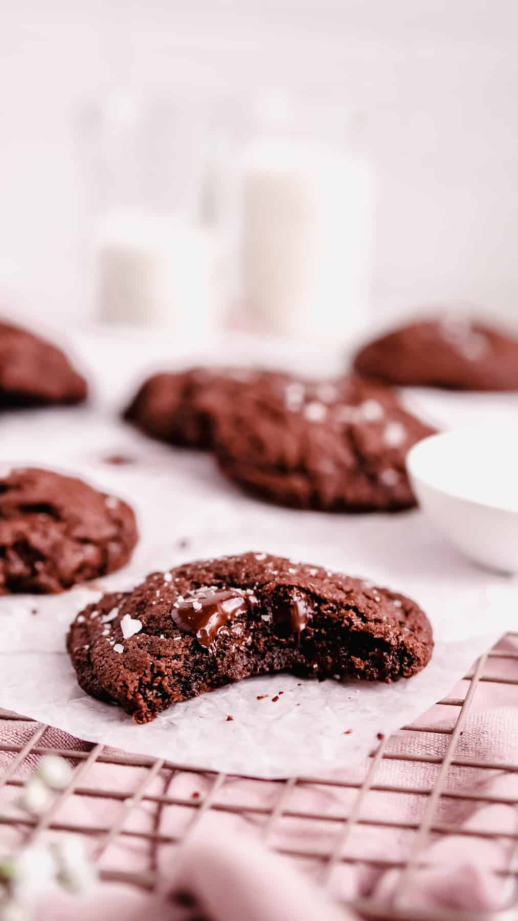 chocolate chip cookies on a wire tray with a bite out of one.