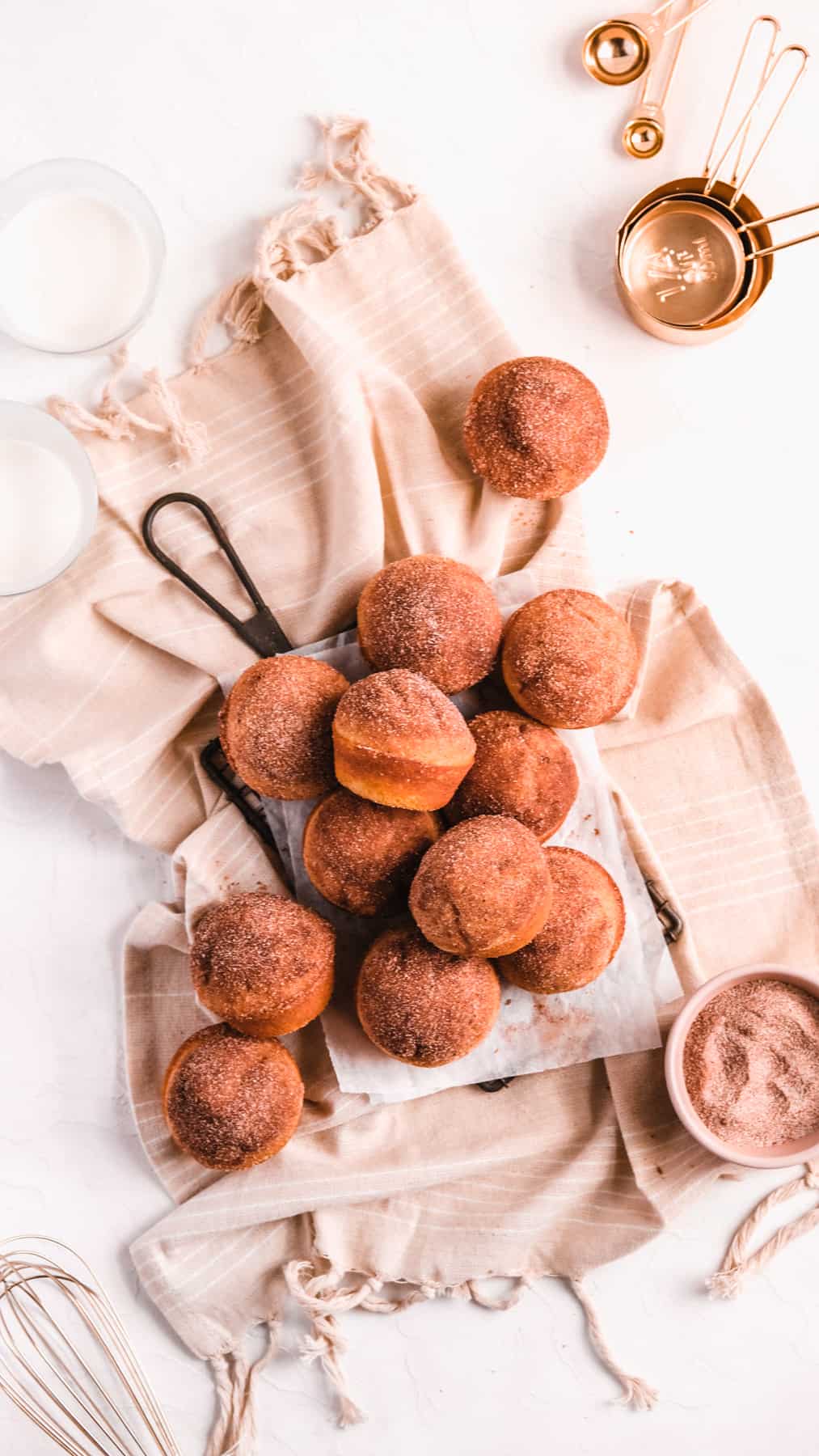 Cinnamon Donut Muffins on a wire rack with baking utensils around them