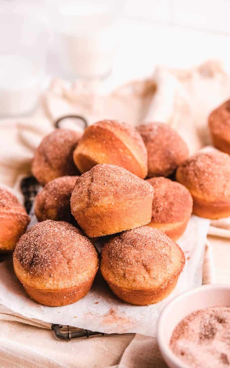 Cinnamon Donut Muffins on a wire rack with baking utensils around them