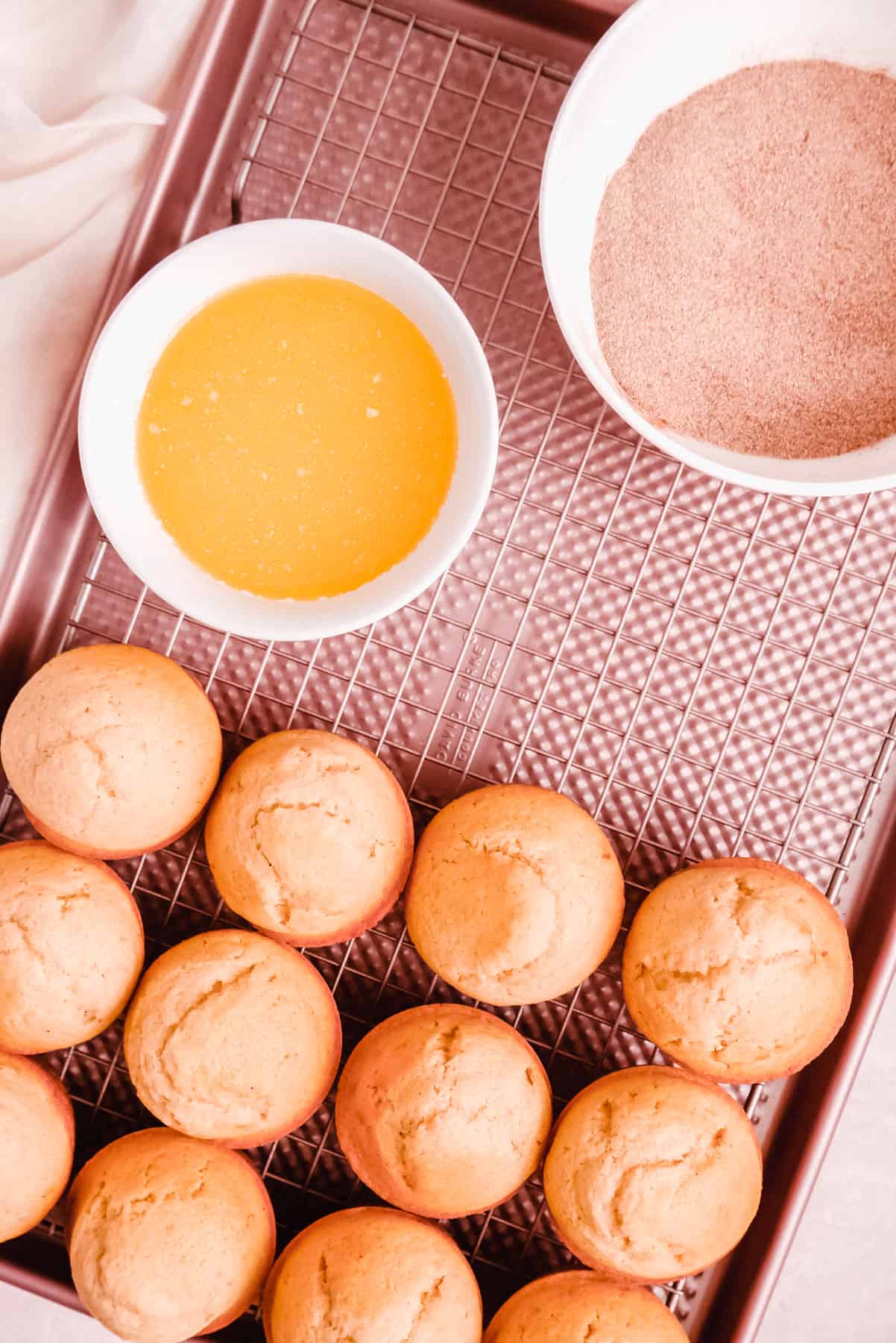 Cinnamon Donut Muffins on a cooling rack with butter and cinnamon and sugar