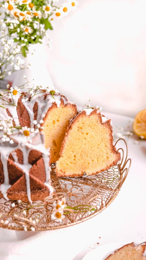 lemon bundt cake on a gold cake plate with lemons