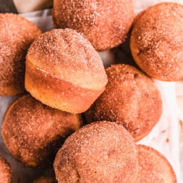 Cinnamon Donut Muffins on a wire rack with baking utensils around them.