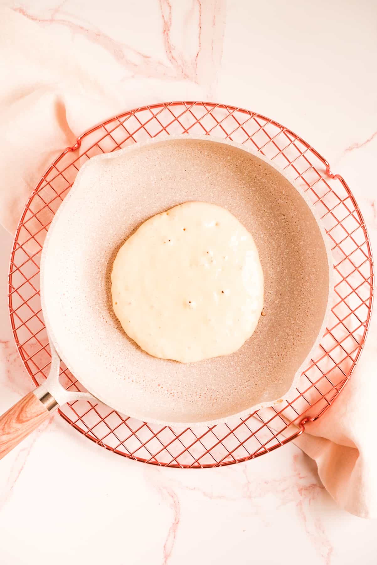 buttermilk pancake batter cooking in a pan on a wire rack