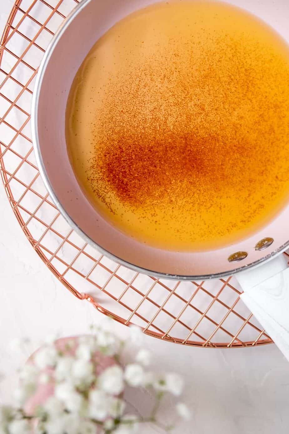 browned butter in a pink pan on a copper wire rack with flowers on the table