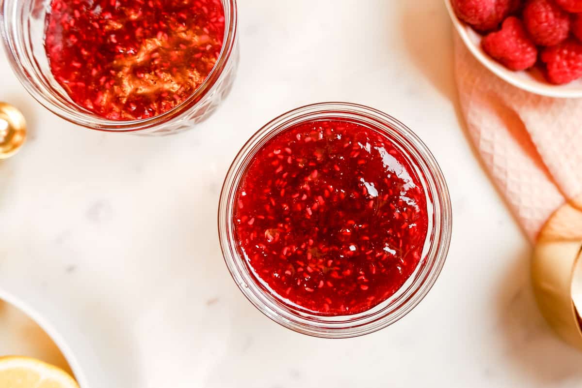 red raspberry jam in a mason jar with a second jar to the side.