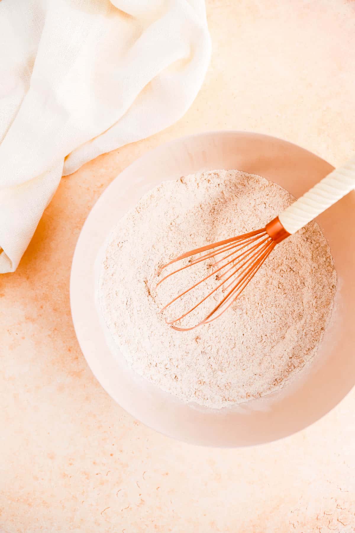 the dry ingredients for carrot cake in a mixing bowl with a whisk.