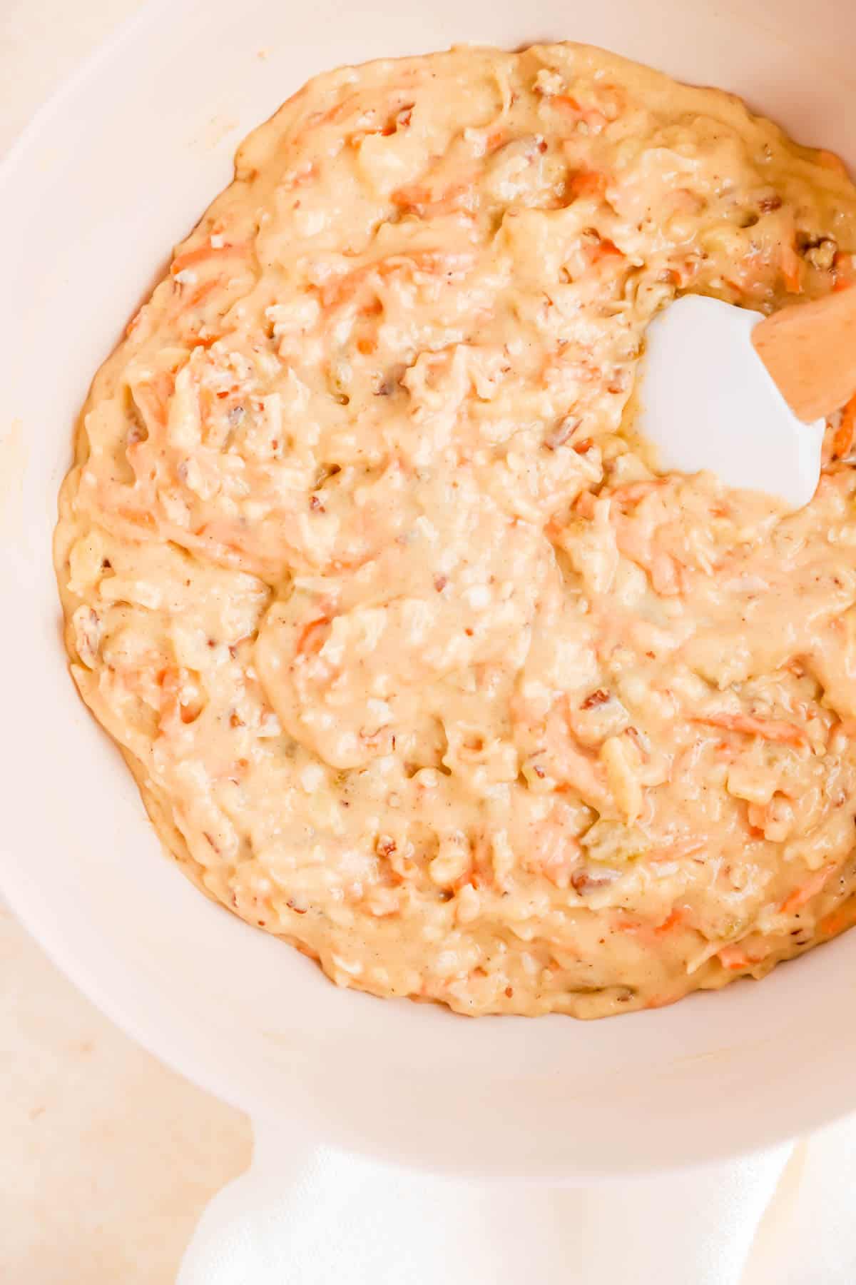 complete carrot cake with pineapple batter in a bowl with a spatula.