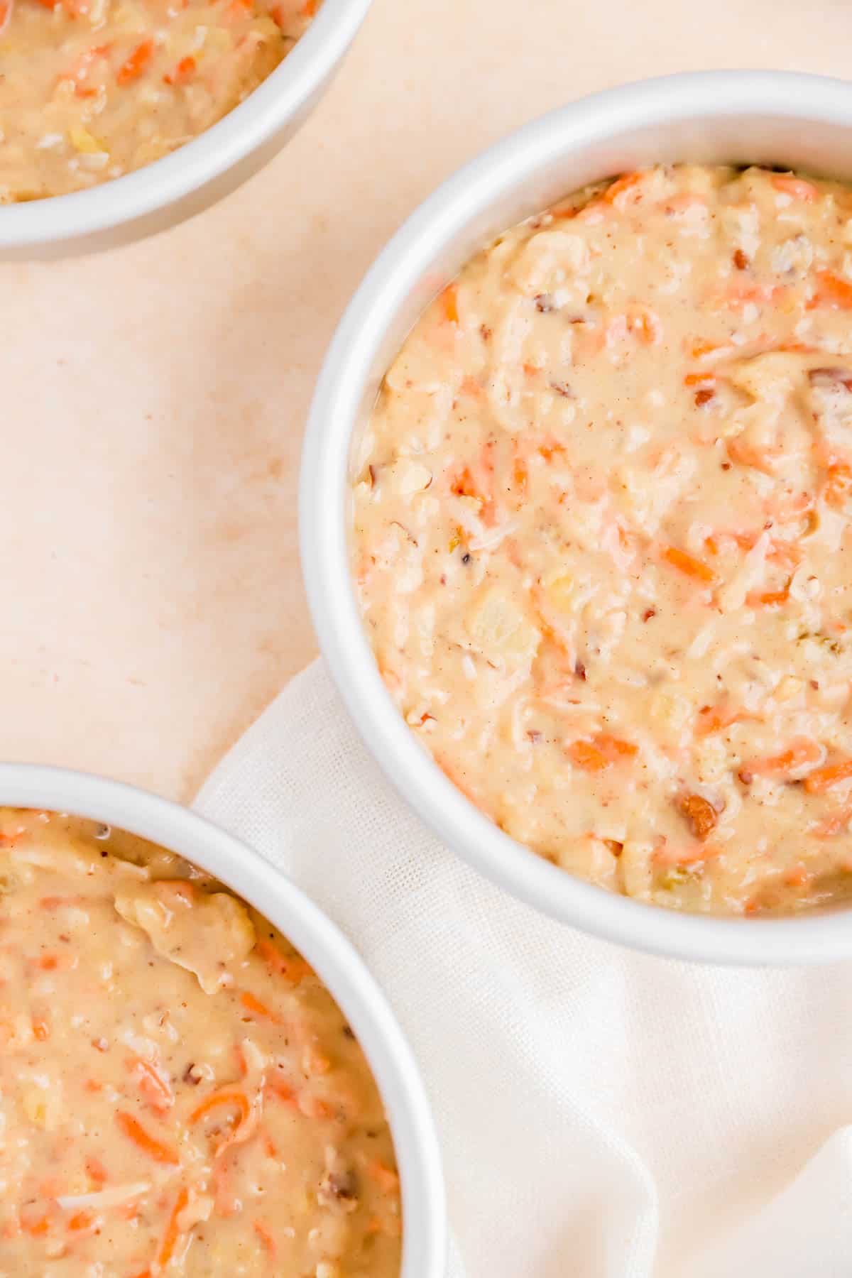 carrot cake with pineapple batter in round cake pans on a white linen.