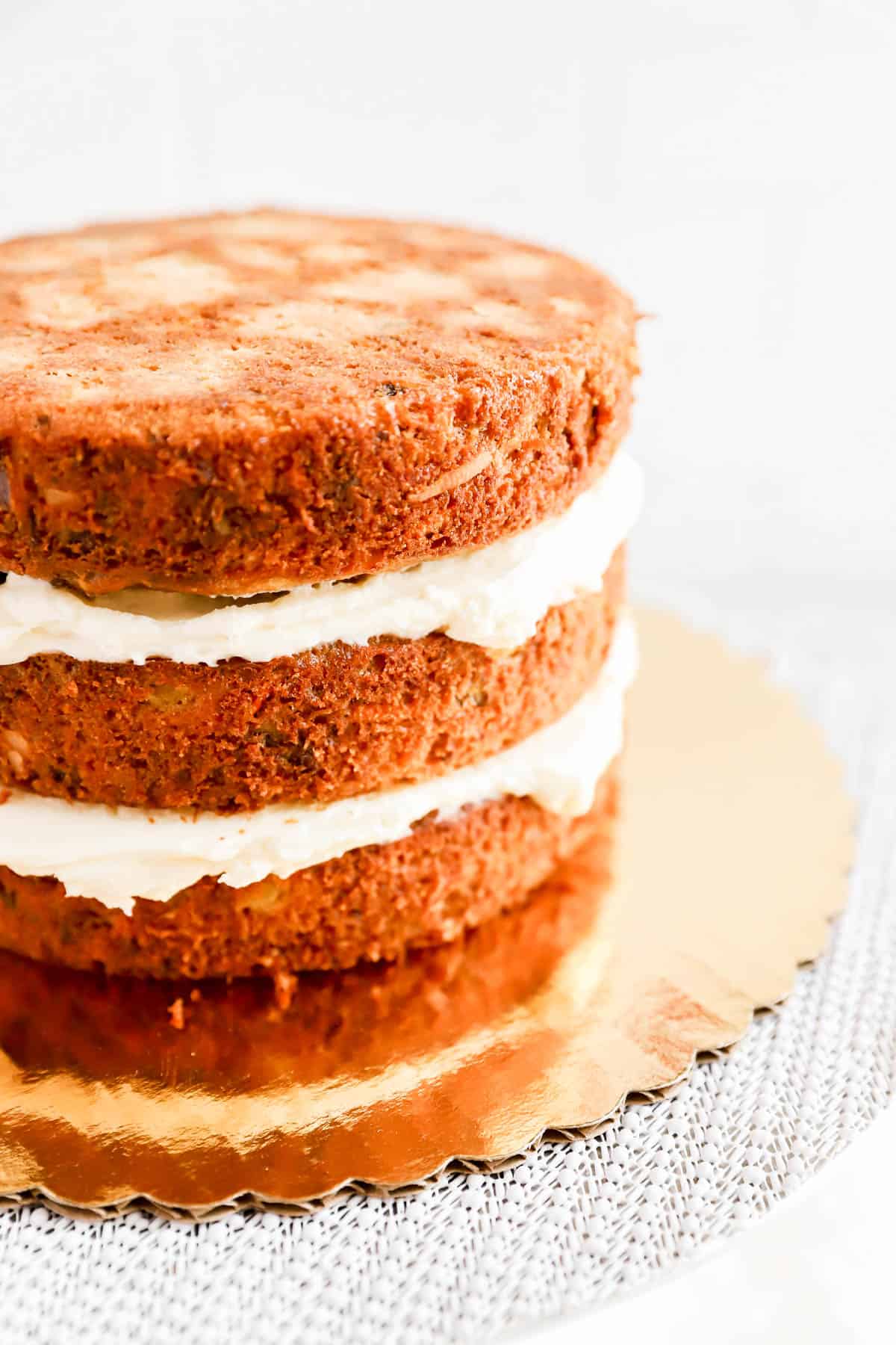 3 baked round carrot cake layers stacked and filled with cream cheese frosting.