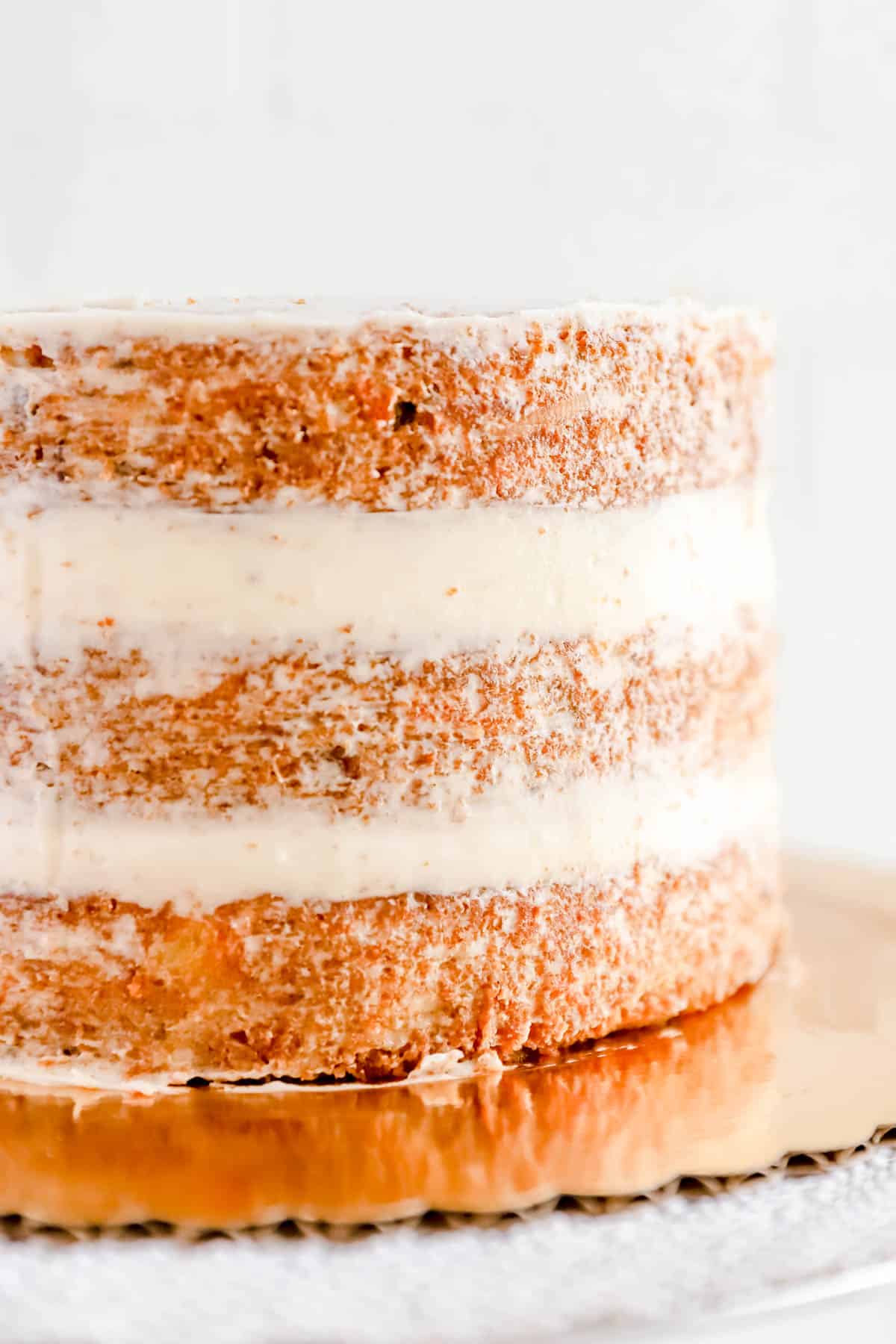 3 baked round carrot cake layers filled and crumb coated with cream cheese frosting.