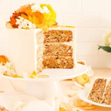 a carrot cake on a cake plate with a few slices cut our and on plates.