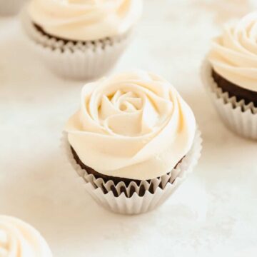 a close up of chocolate cupcakes with rosettes of cream cheese frosting on top.
