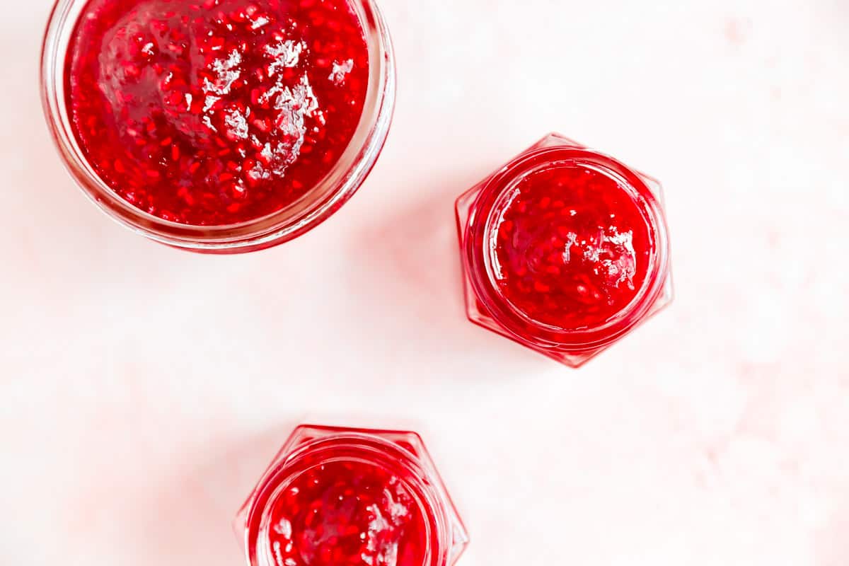 1 big and 2 mini jars filled with homemade raspberry jam.