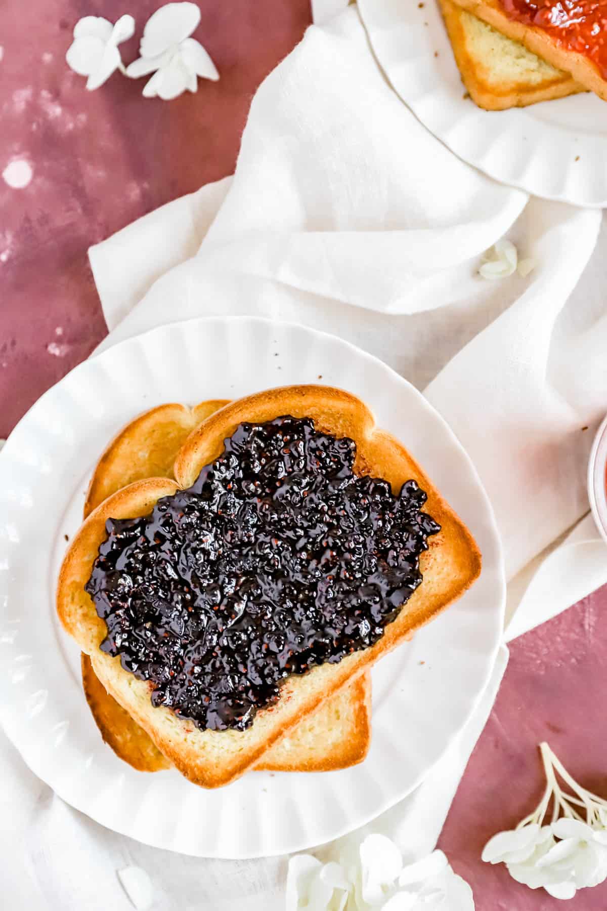 a slice of toast with homemade black raspberry jam on it and another piece of toast below.