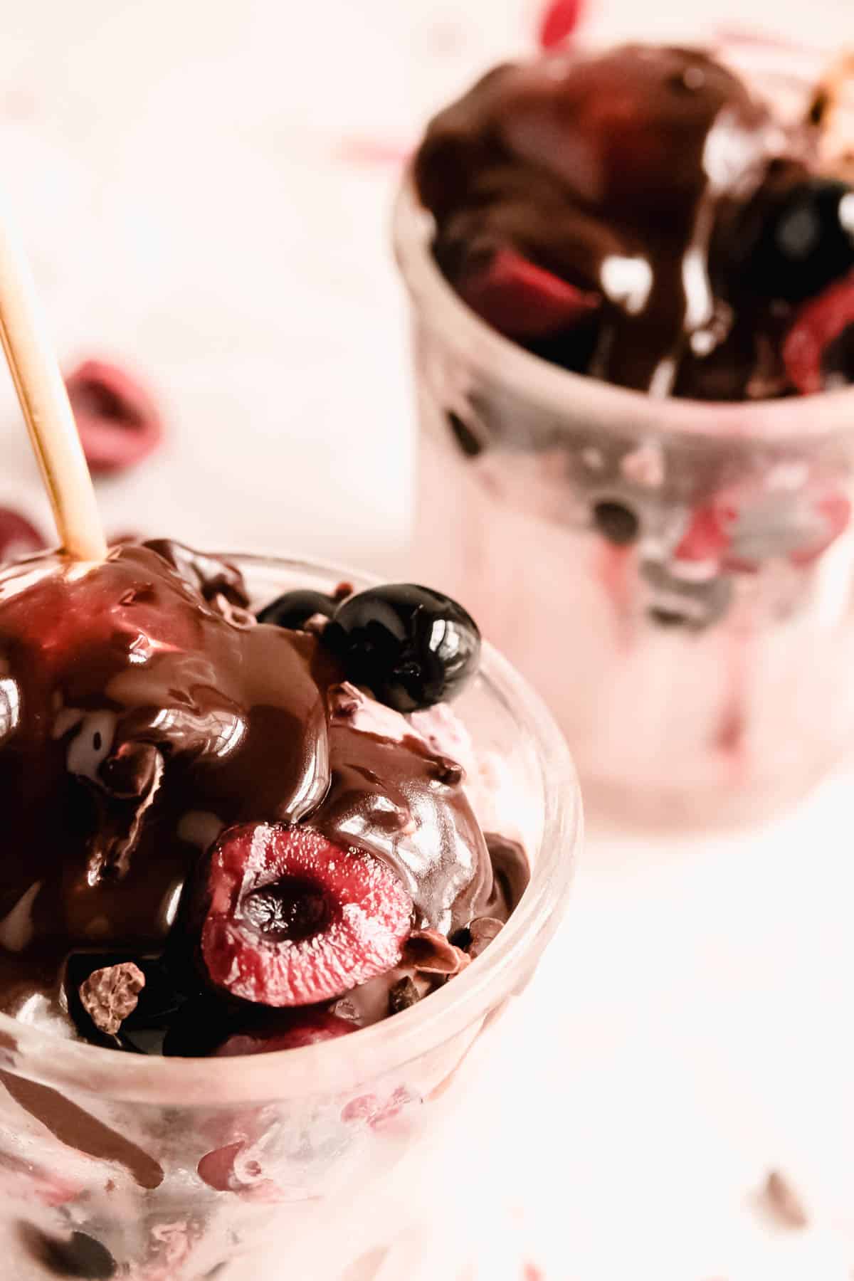cherry ice cream and sundaes in glass jars close-up with homemade fudge sauce on top.