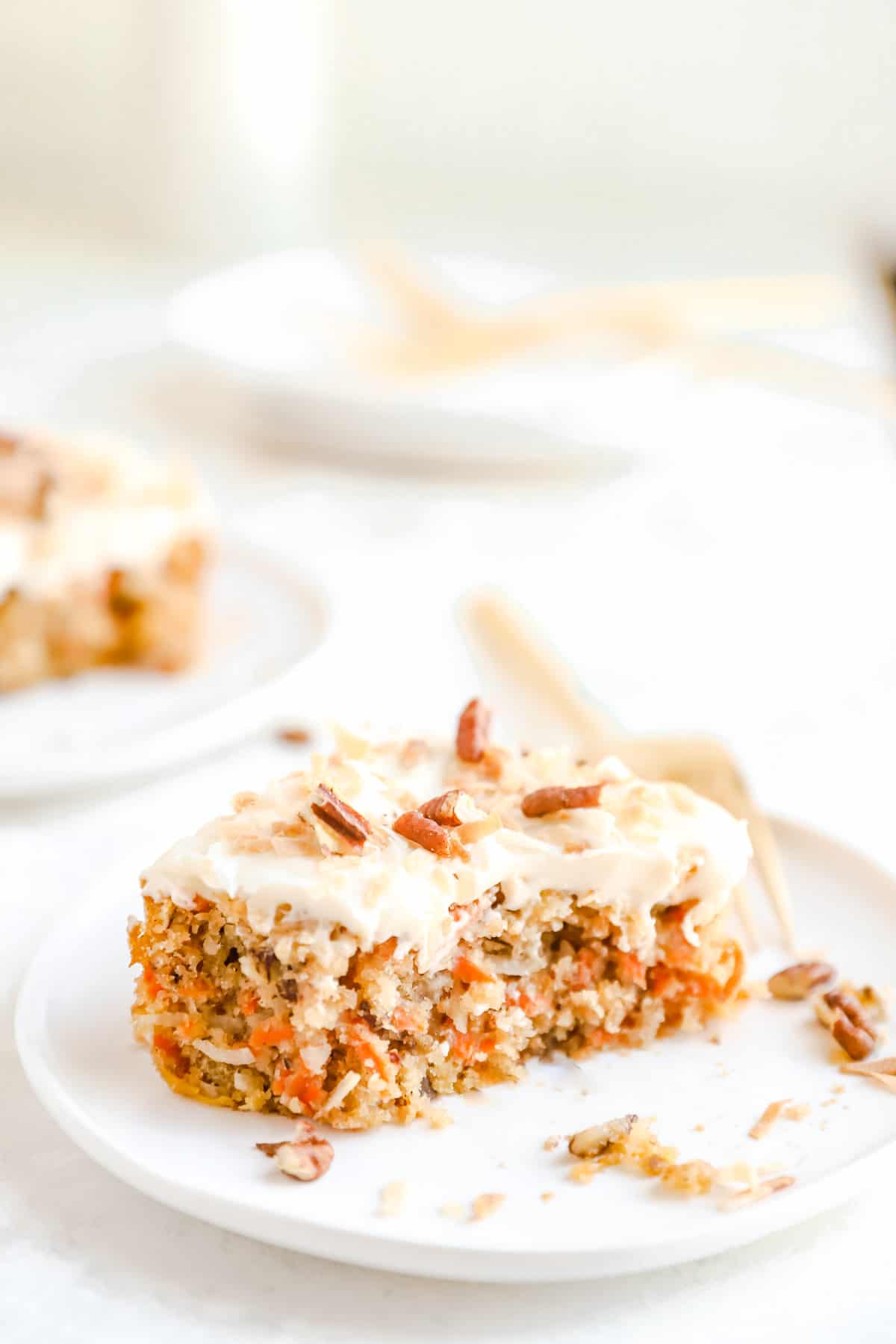 a square of old-fashioned carrot cake on a plate with whipped cream cheese frosting on top.
