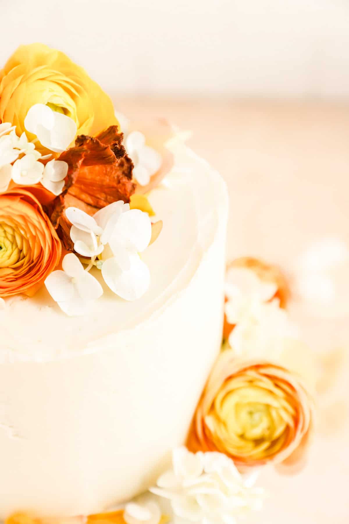 a close up of a cream cheese frosted carrot cake decorated with flowers.