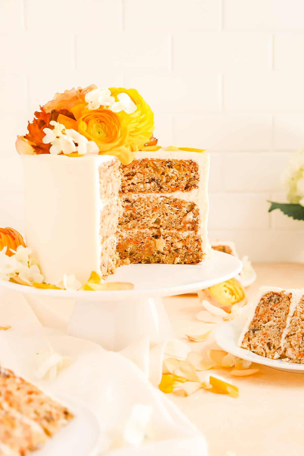 a carrot cake on a cake plate with a few slices cut our and on plates.