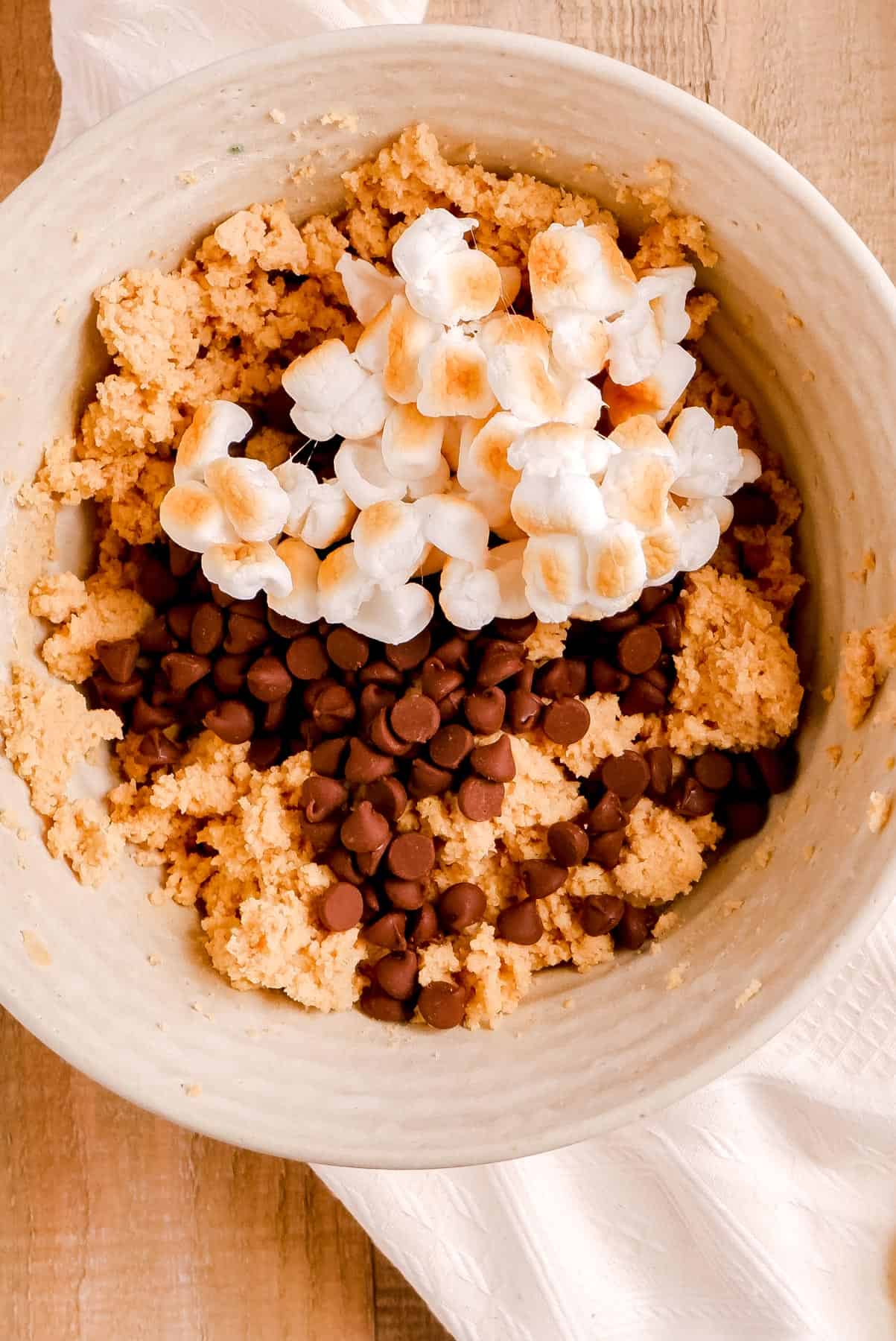 chewy smores cookies batter with chocolate chips and marshmalows on top.