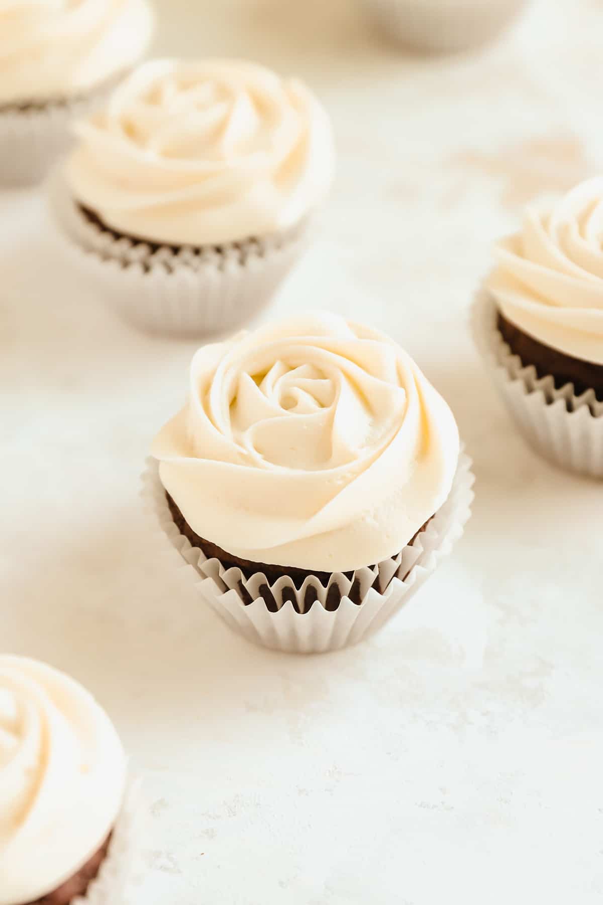 a close up of chocolate cupcakes with rosettes of cream cheese frosting on top.