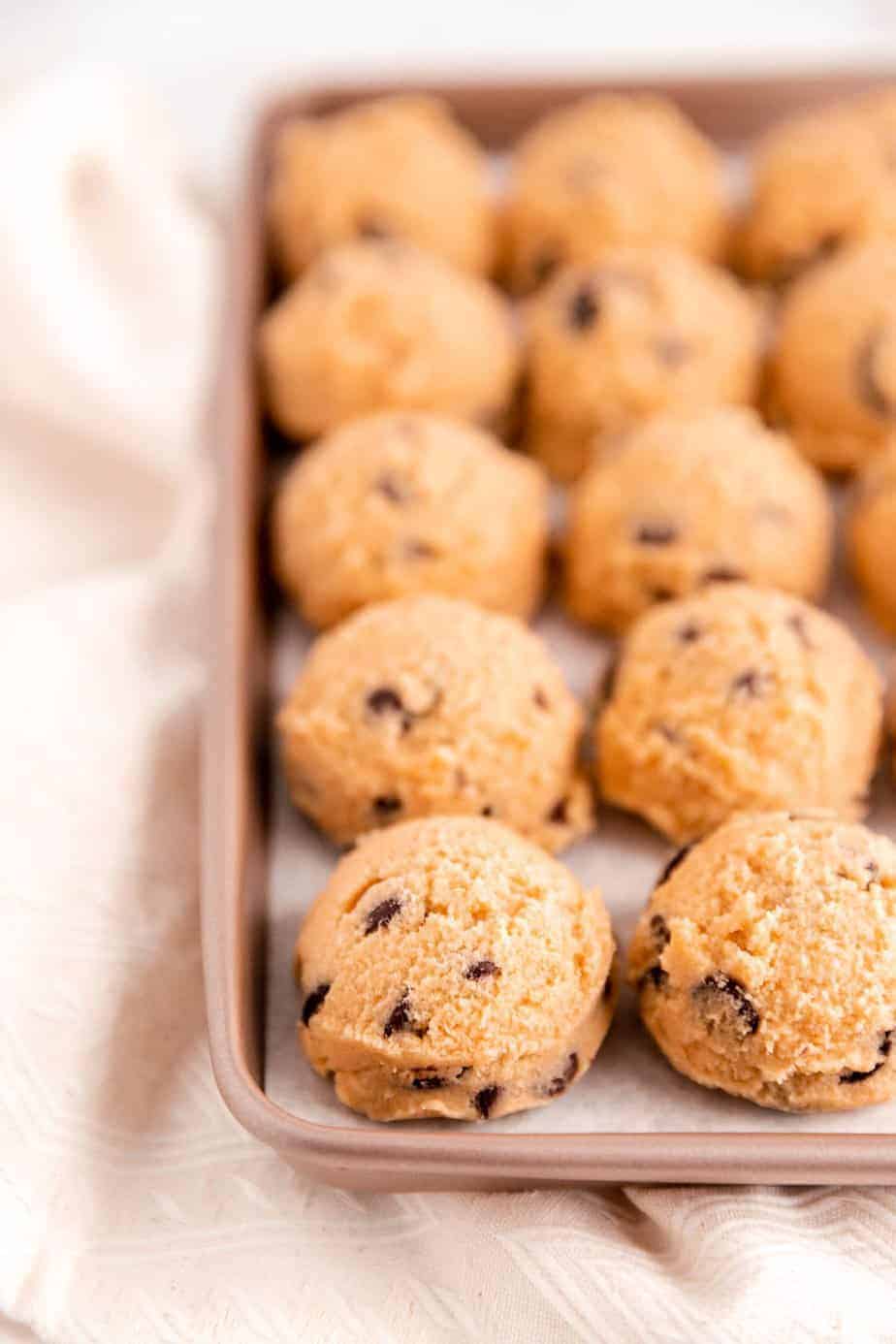 a full golden cookie sheet filled with chocolate chip cookie dough balls.
