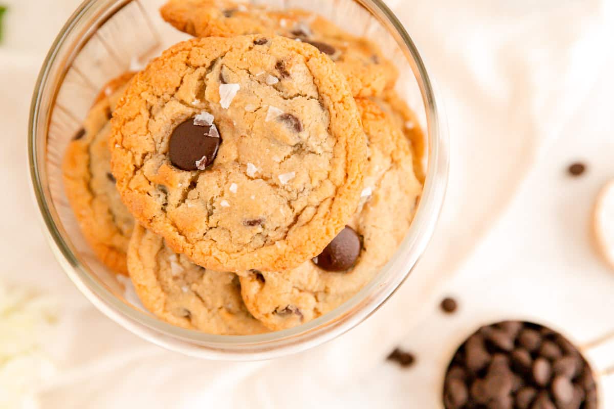 A jar of chocolate chip cookies from above with a cup of chocolate chip cookies below