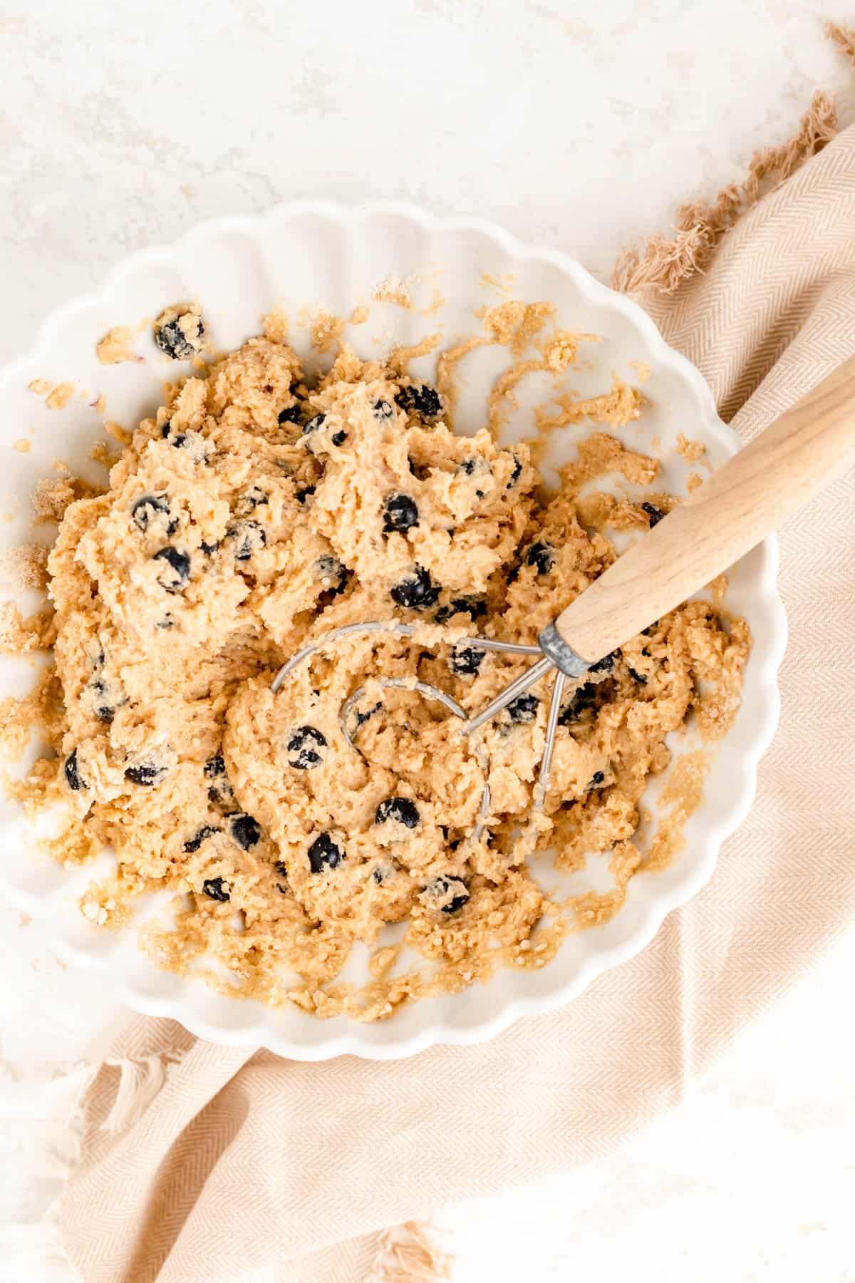 fully mixed blueberry scone batter in a white bowl with a dough whisk in it