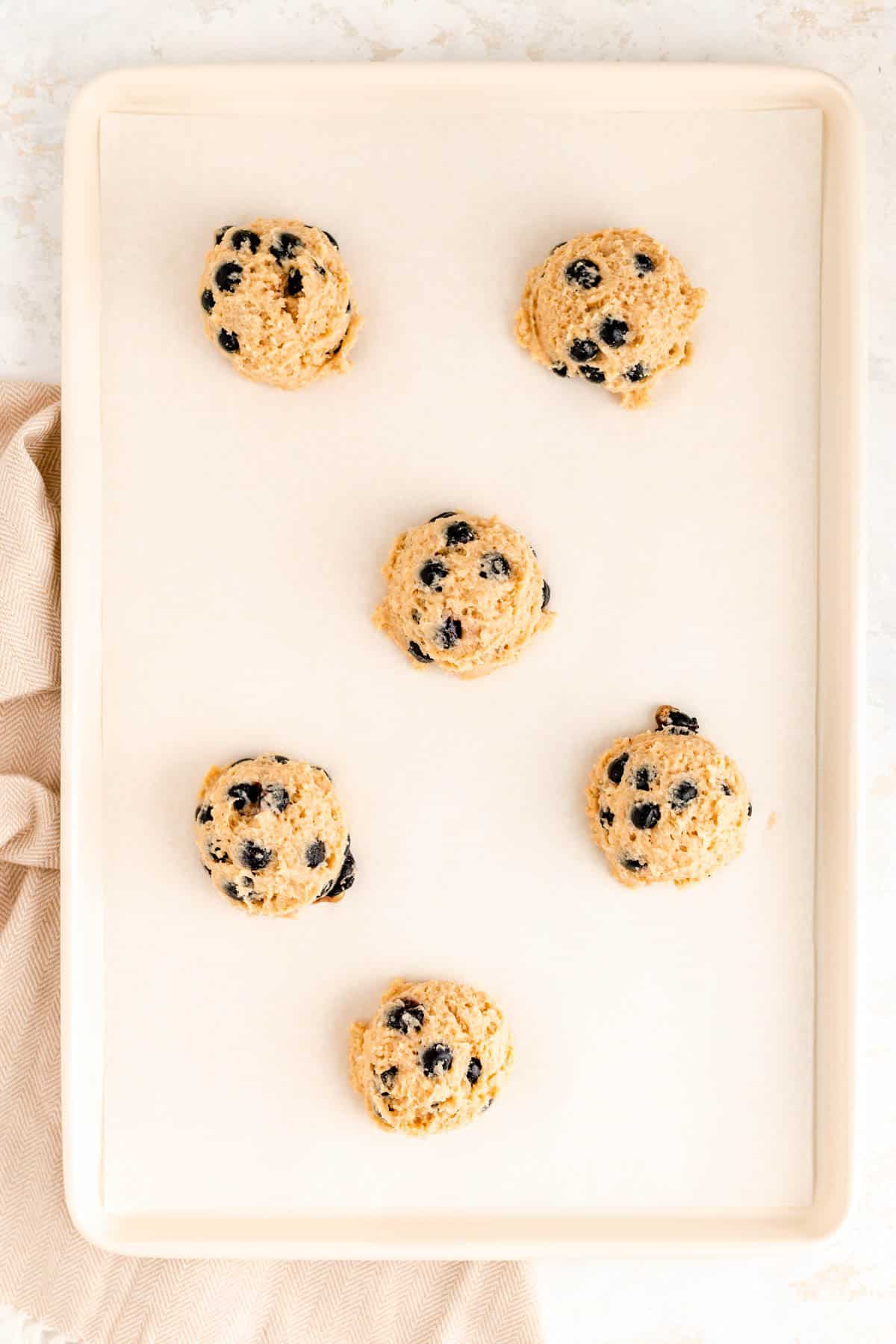 scooped blueberry scone batter on a white parchment lined baking sheet