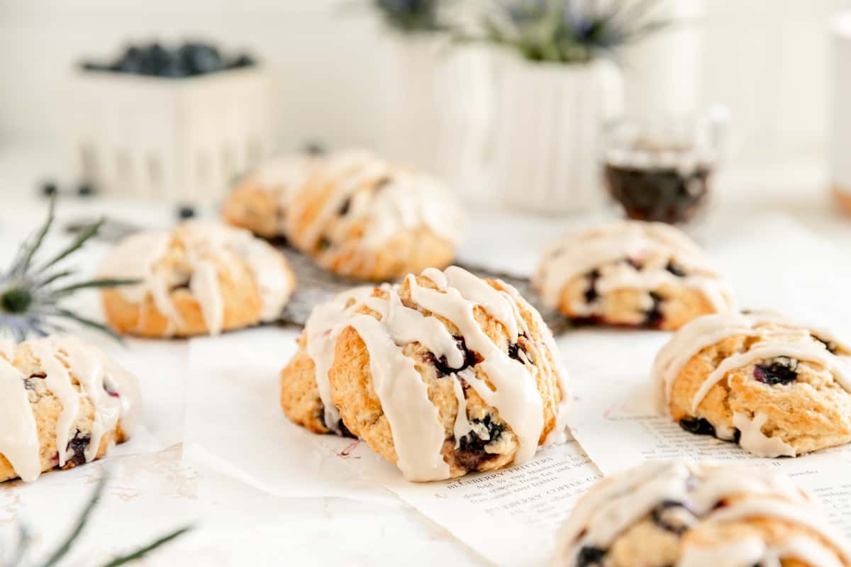 a glazed blueberry scones leaning on another scone on torn out recipes pages