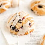 close up of a glazed maple blueberry scone on torn out recipe pages