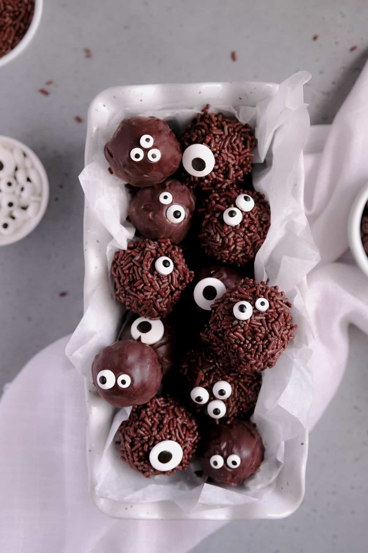 chocolate brownie truffles with sprinkles and candy eyes piled in a white dish