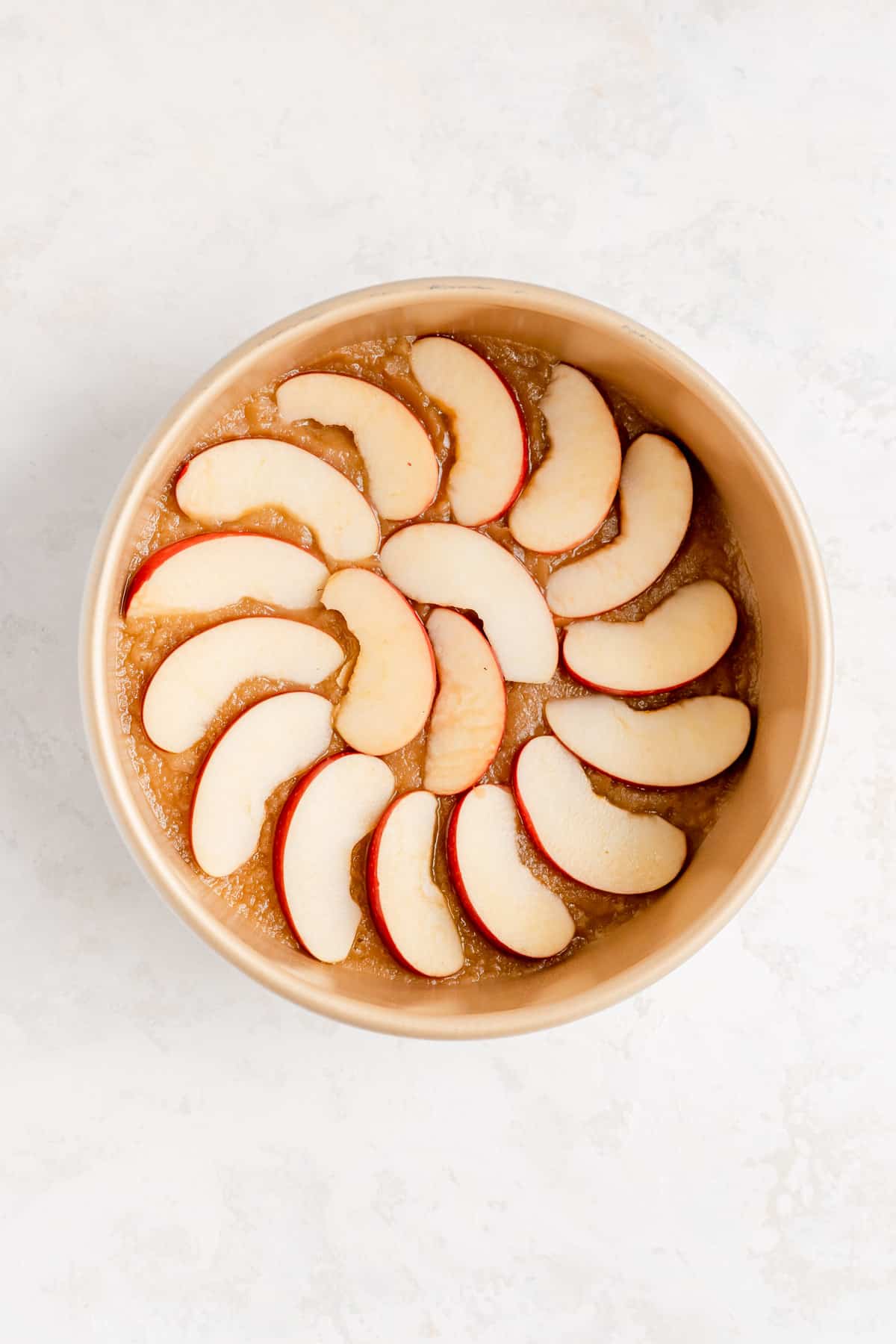 a gold cake pan with a caramel in the bottom and apples in a ring on top of it