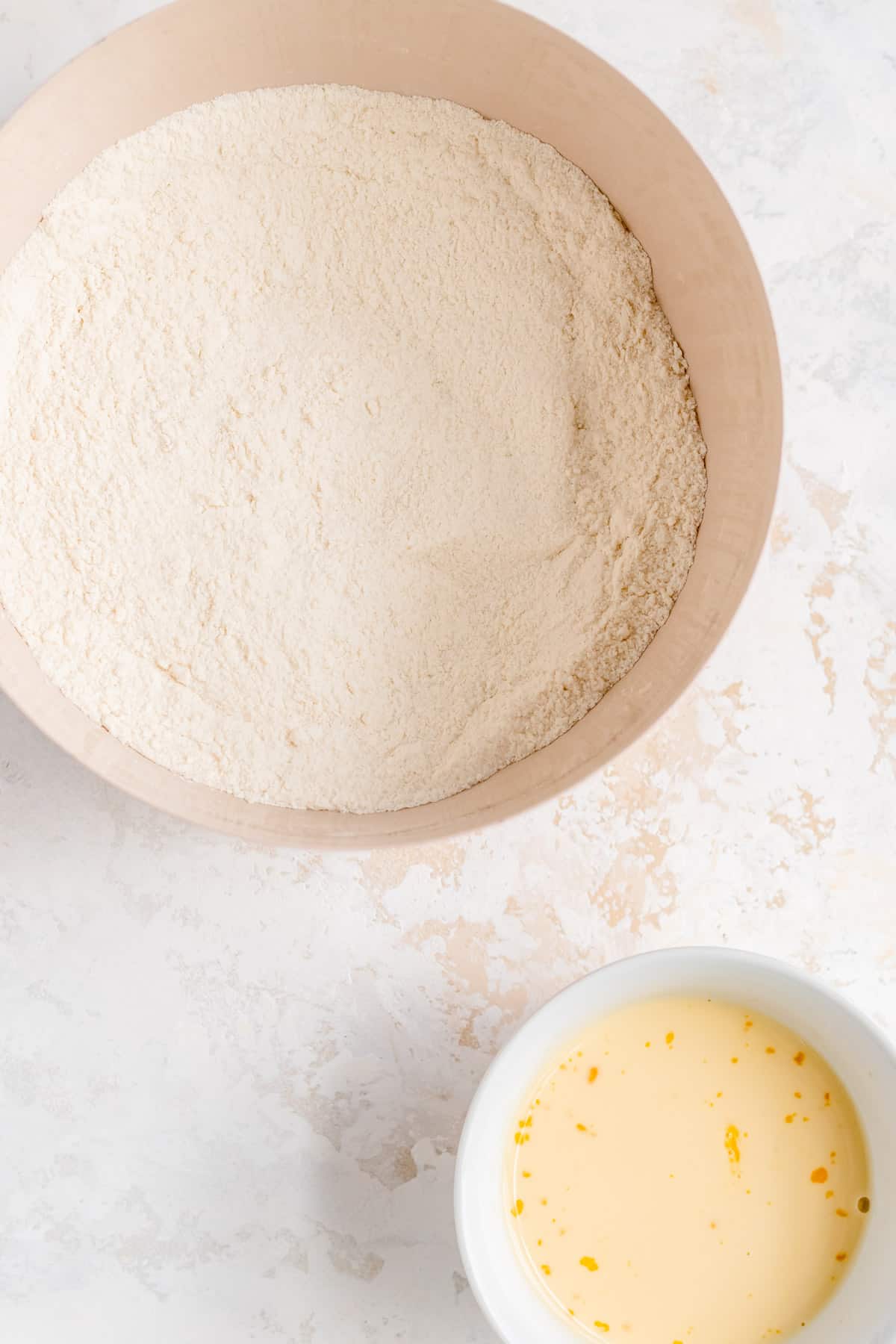 a bowl of dry ingredients and a bowl of wet ingredients on a white background