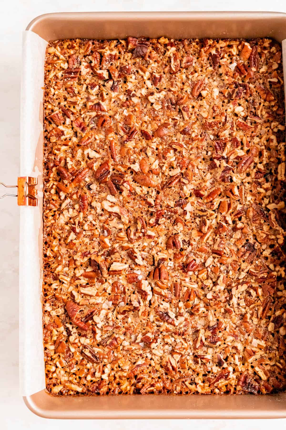 fully baked, golden brown pecan pie bars in a parchment-lined gold pan