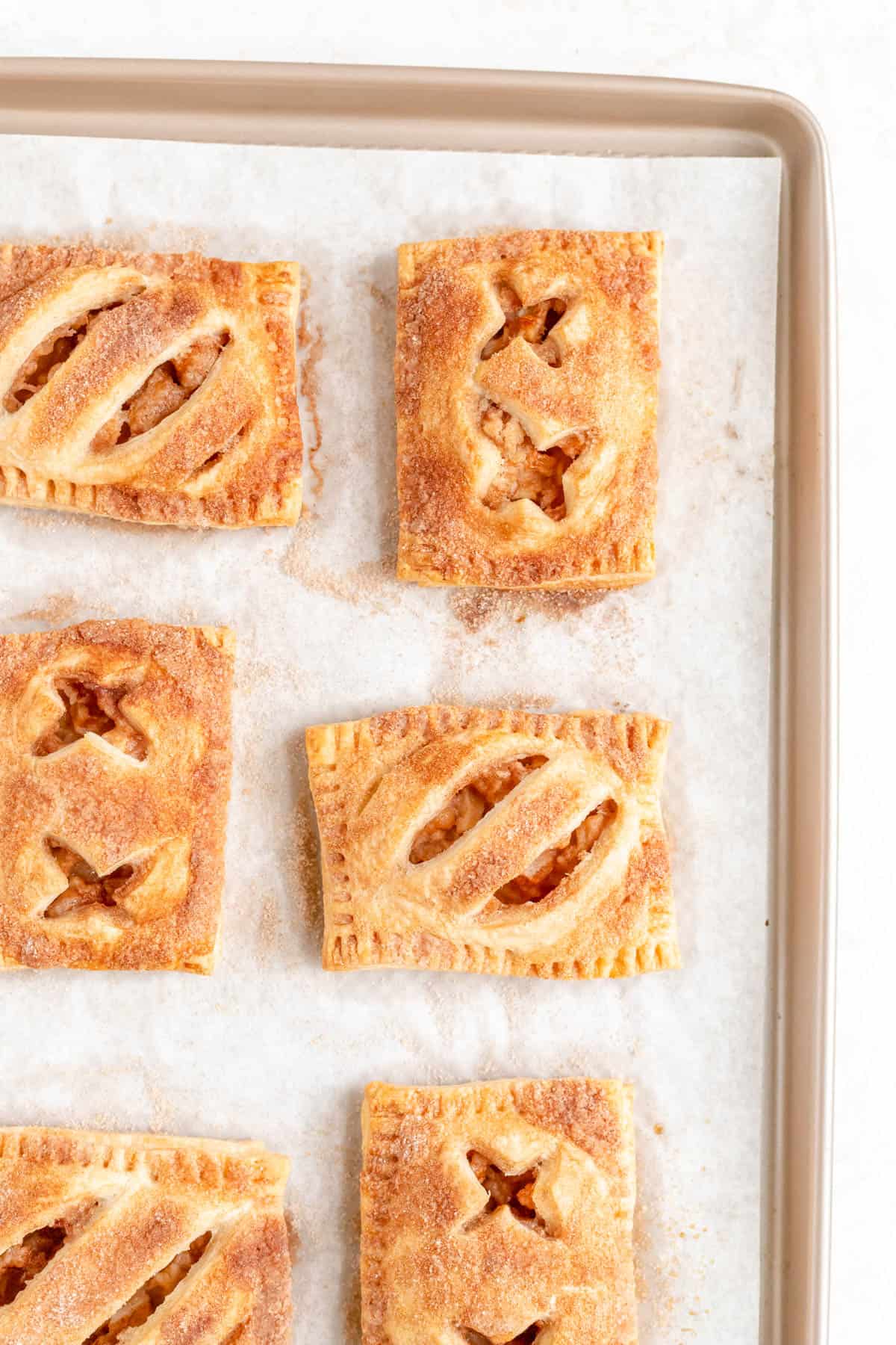 baked apple hand pies on a parchment-lined gold sheet pan