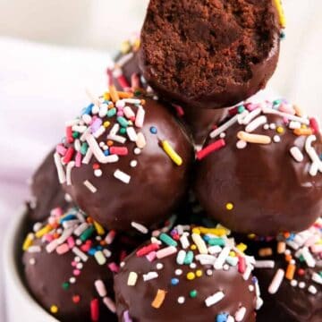 a stack of brownie truffles with sprinkles on them with the top one bit in half.