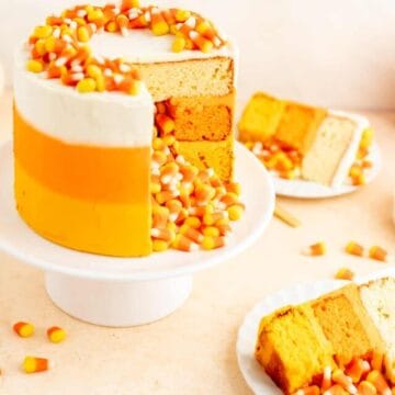 candy corn decorated cake with candy corn spilling out of middle with slices on plates