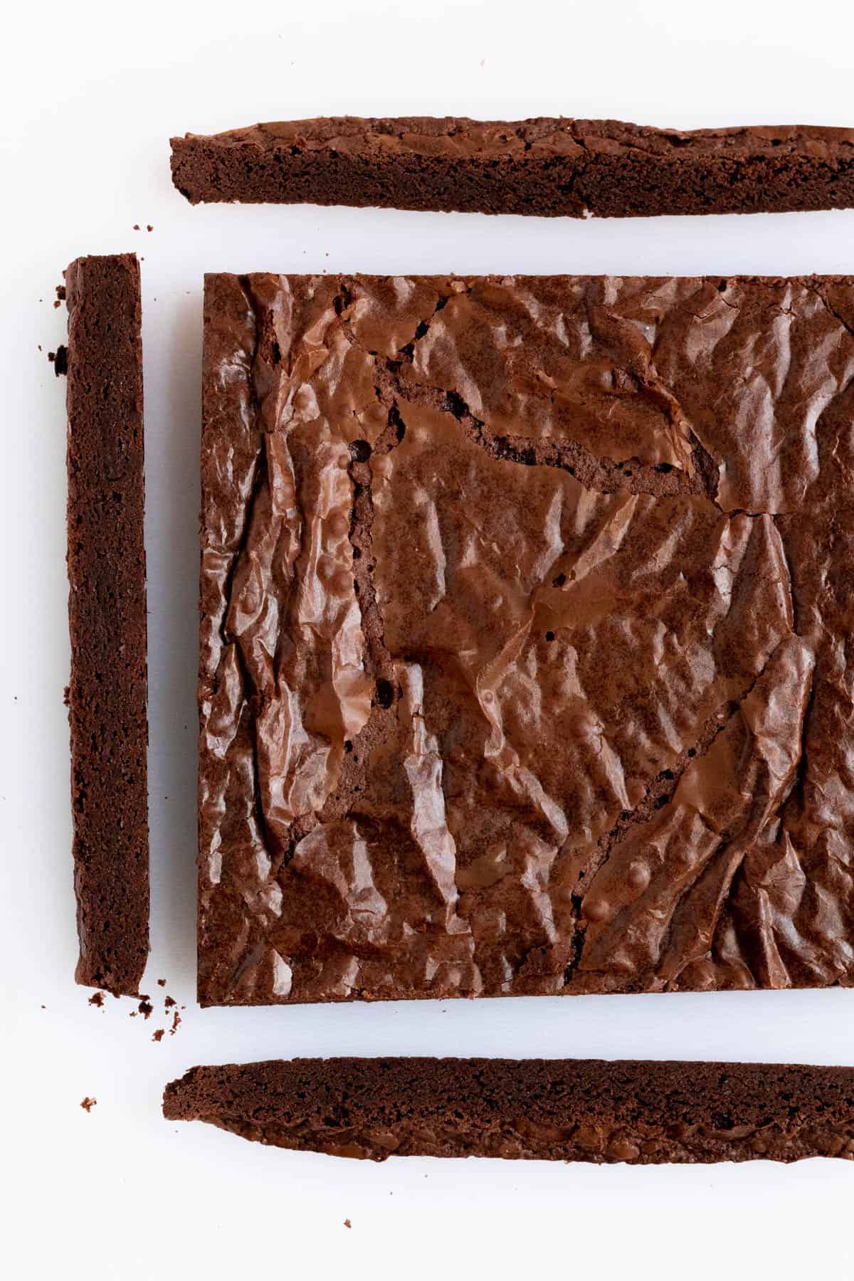 fudgy brownies with the edge trimmed off on a white cutting board