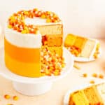 candy corn decorated cake with candy corn spilling out of middle with slices on plates